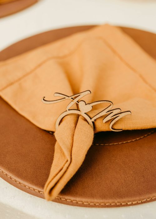 Close-up of a stylish wedding table setting featuring a folded napkin and personalized napkin ring.